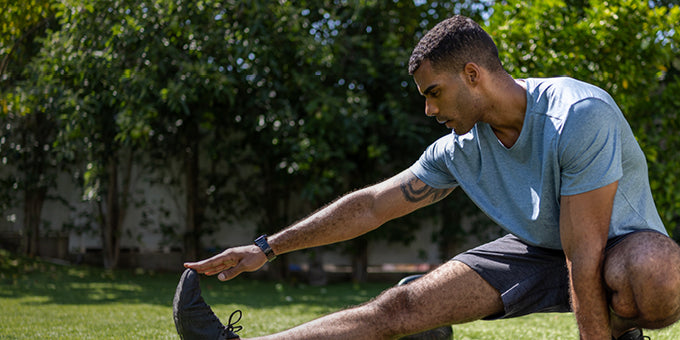 Man stretching outdoors with trees in the background