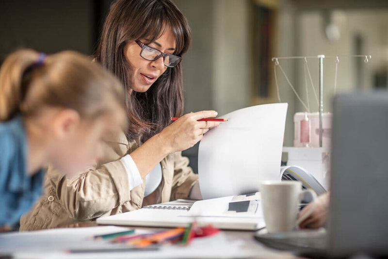 Woman working next to child drawing